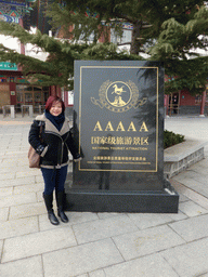 Miaomiao at a stone with inscription of the AAAAA-rating near the entrance to the Nanshan Mountain Tourist Area