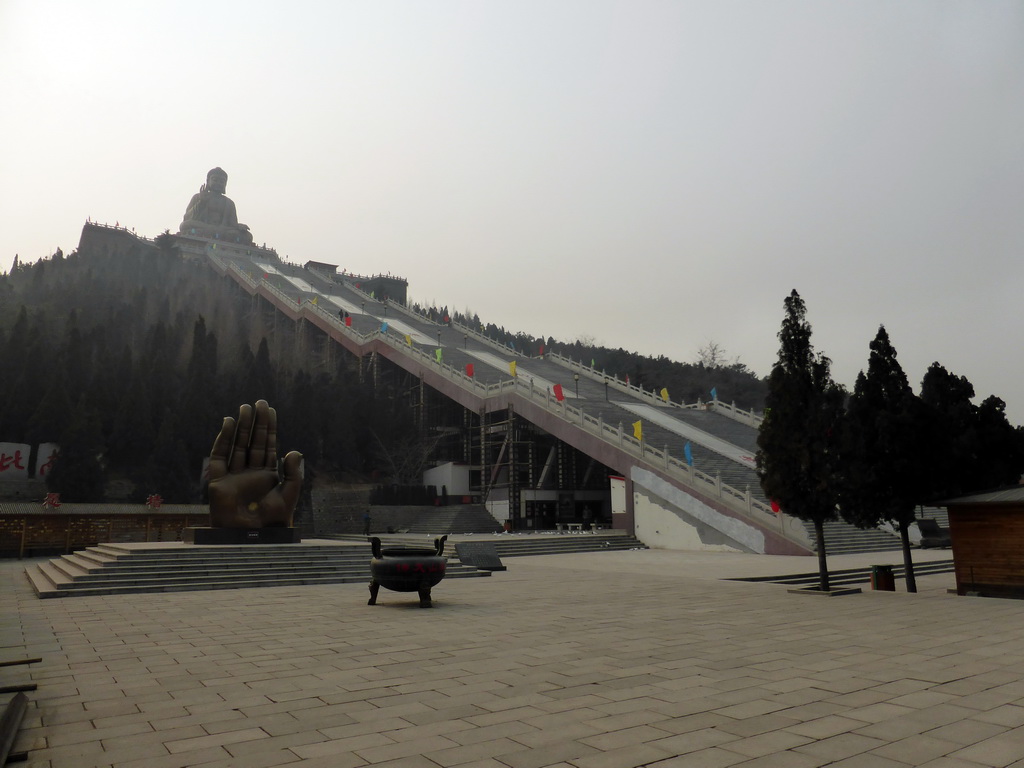 Statue of a hand at the southeastern side of the central square of the Nanshan Temple, and the Nanshan Great Buddha with its staircase