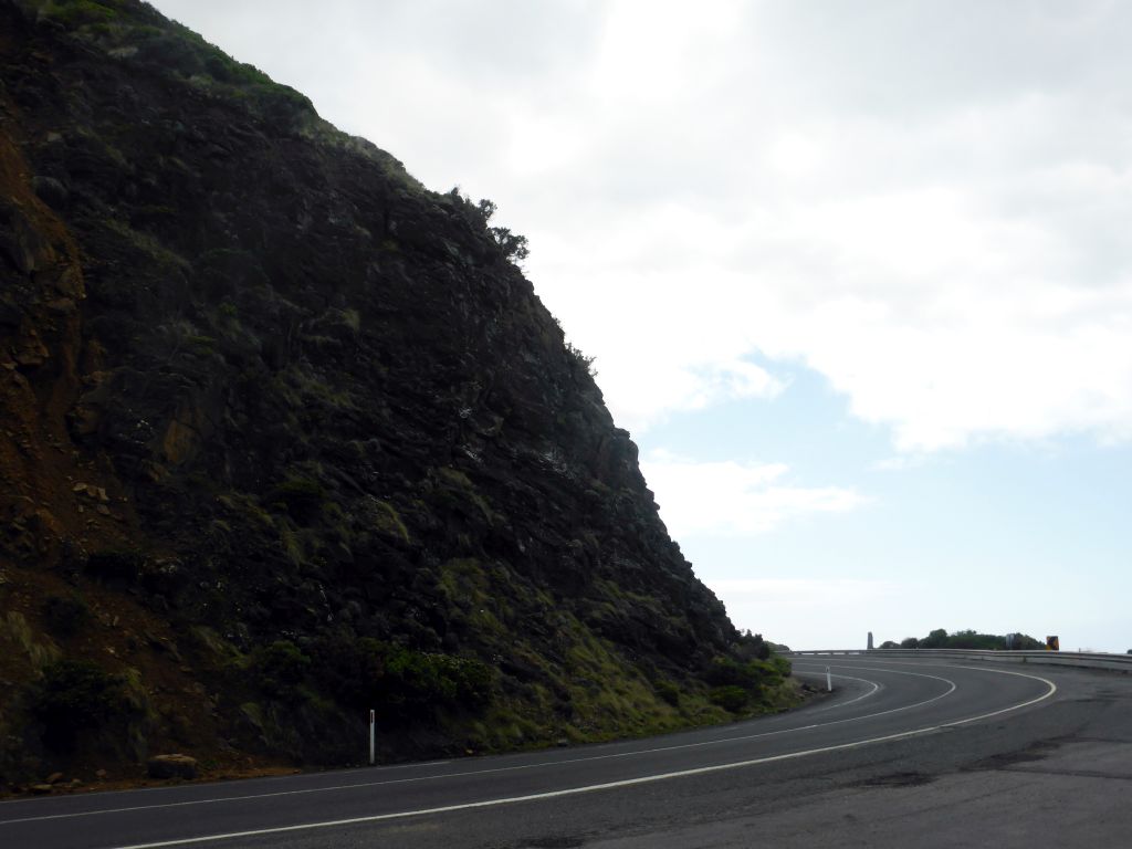 The Great Ocean Road turning around a hill, viewed from a viewing point next to the road