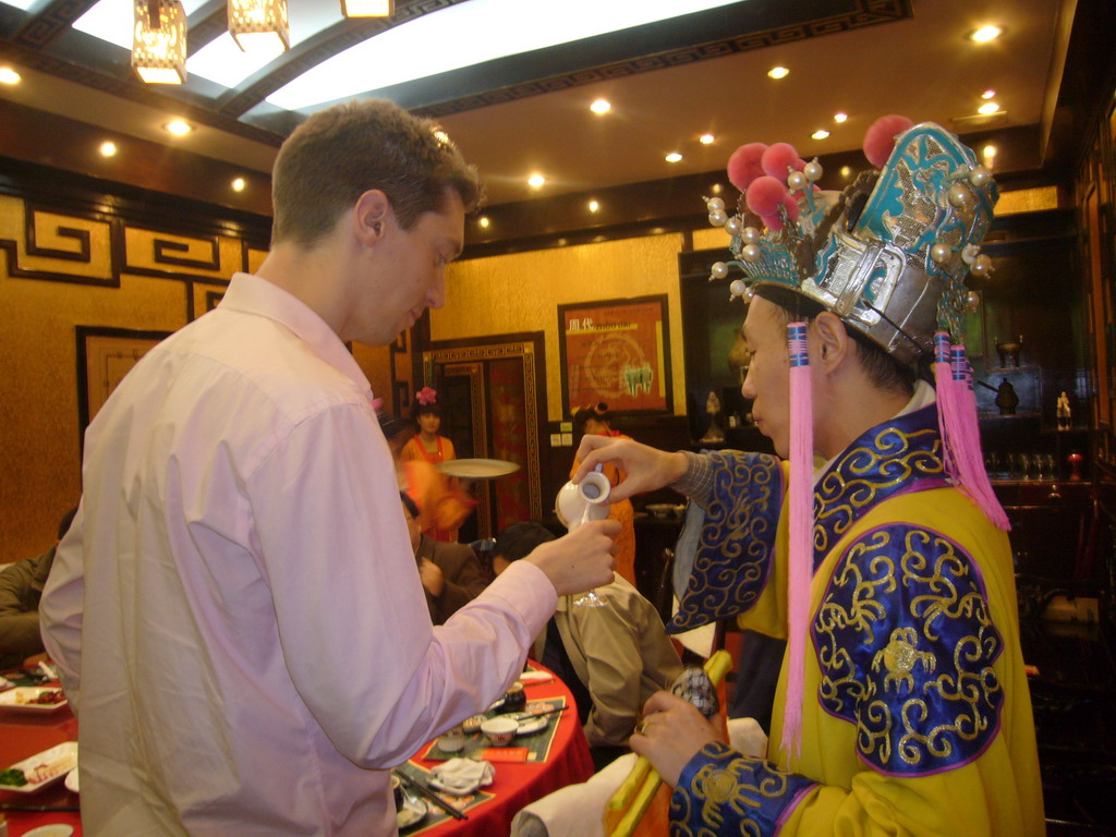 Tim getting a drink as part of a ritual being performed in a restaurant near Luoyang
