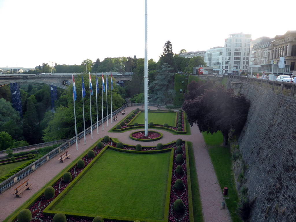 Garden with the flags of Luxembourg and the European Union and the Pont Adolphe bridge over the Vallée de la Pétrusse valley, viewed from the Place de la Constitution square