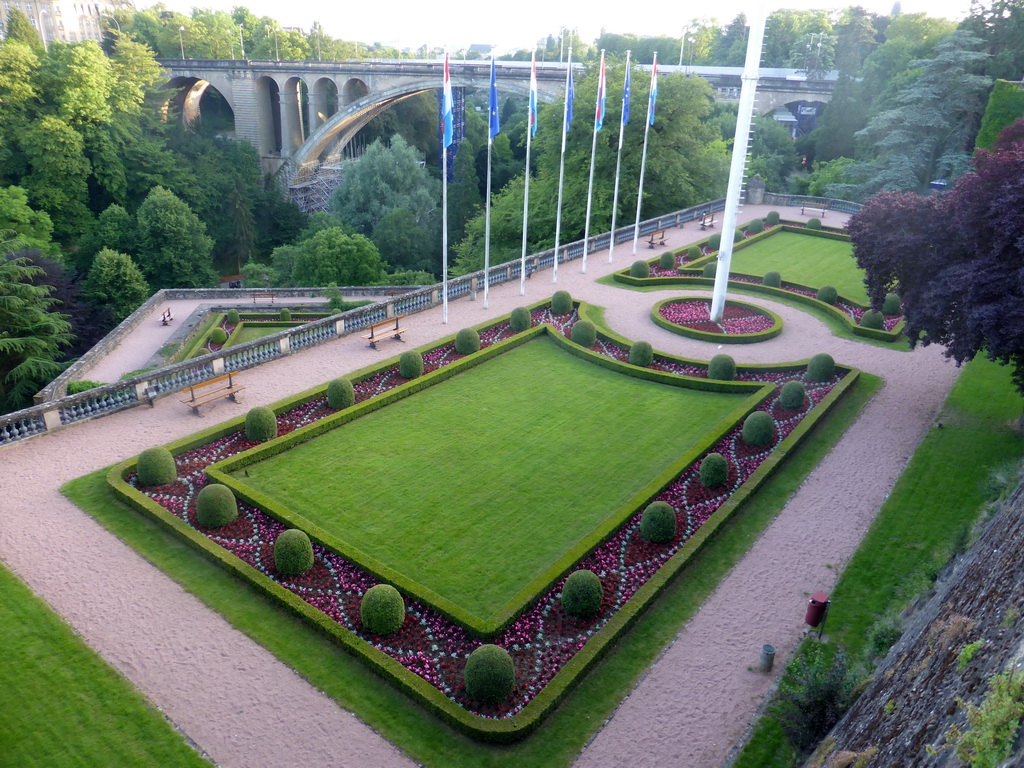 Garden with the flags of Luxembourg and the European Union and the Pont Adolphe bridge over the Vallée de la Pétrusse valley, viewed from the Place de la Constitution square