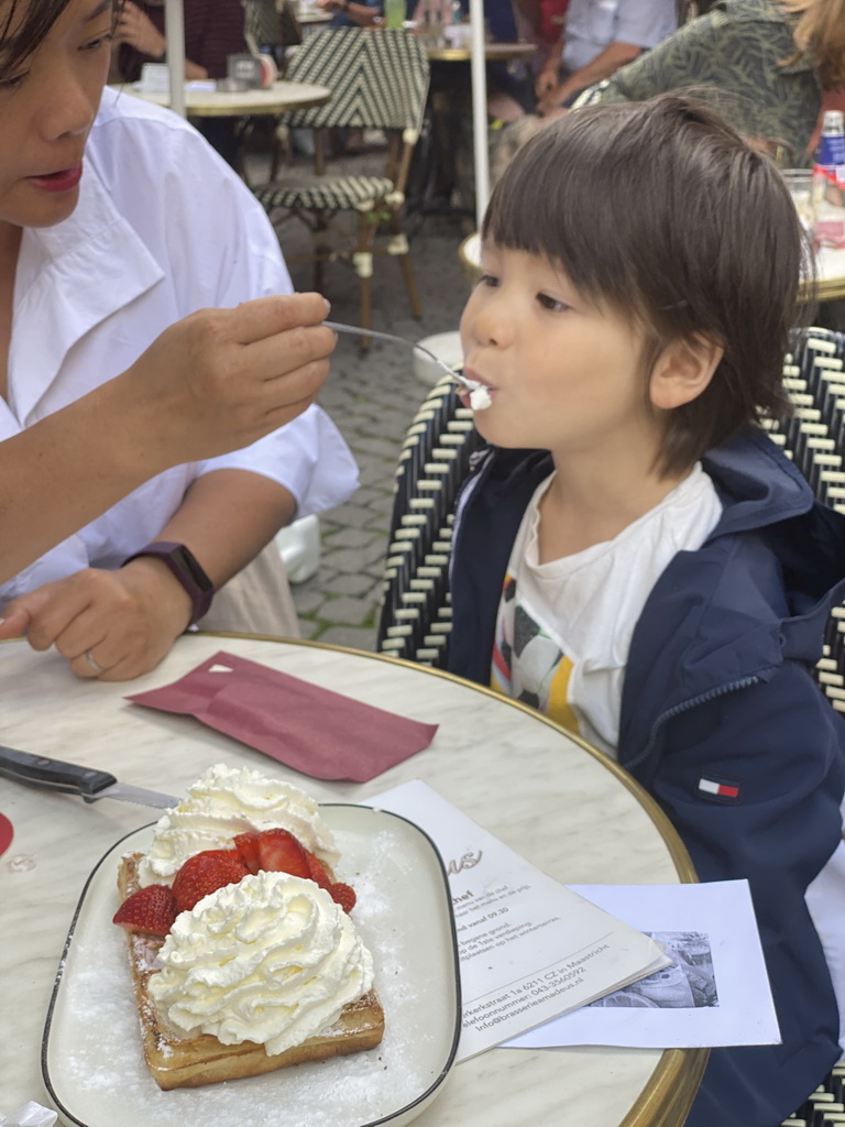 Max eating waffle with strawberries and whipped cream at the terrace of the Brasserie Amadeus restaurant at the Dominicanerplein square