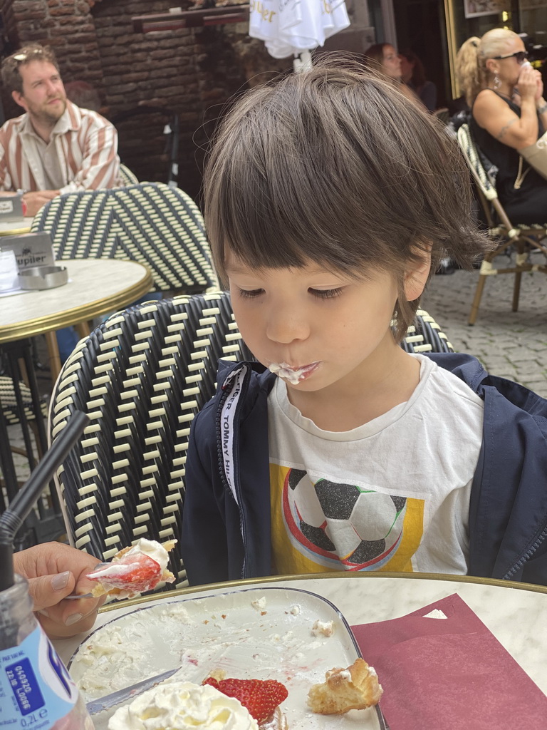 Max eating waffle with strawberries and whipped cream at the terrace of the Brasserie Amadeus restaurant at the Dominicanerplein square