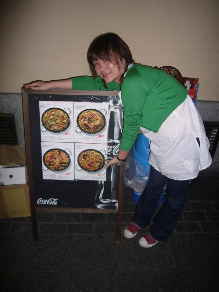 Miaomiao at a poster with paella plates, in a restaurant in the city center