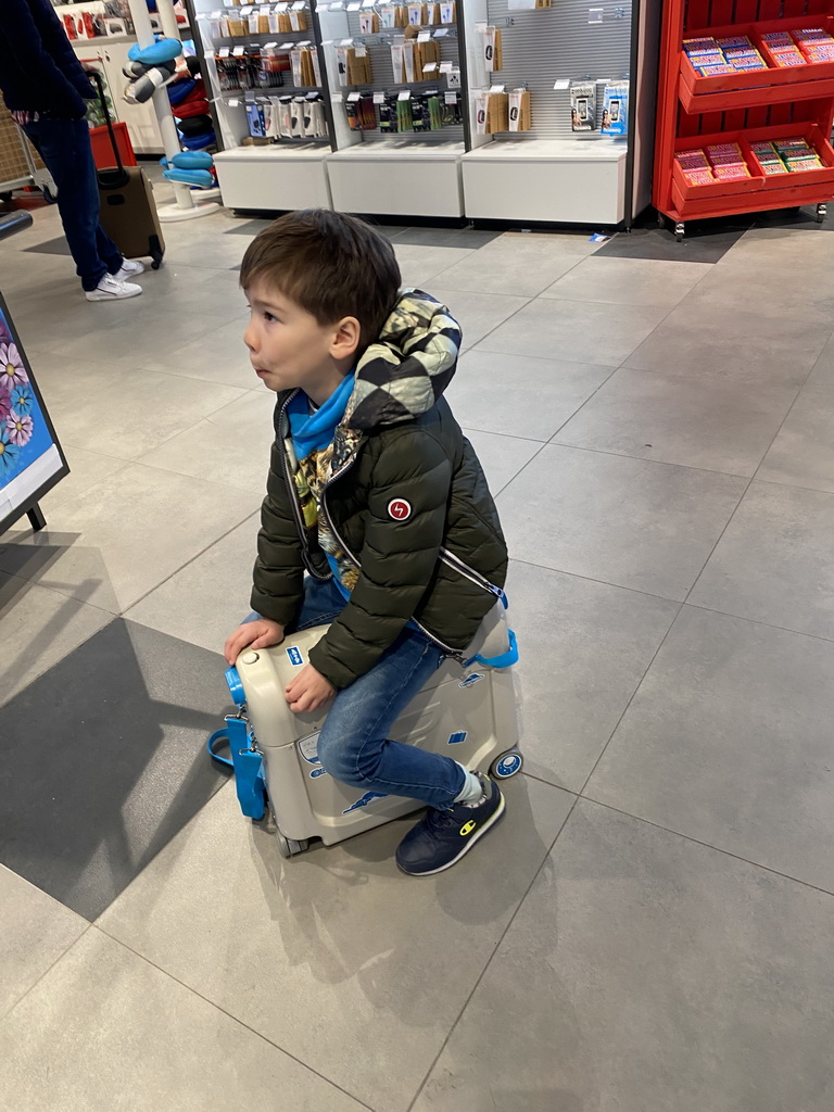 Max on his suitcase at the Travel Plaza shop at Eindhoven Airport