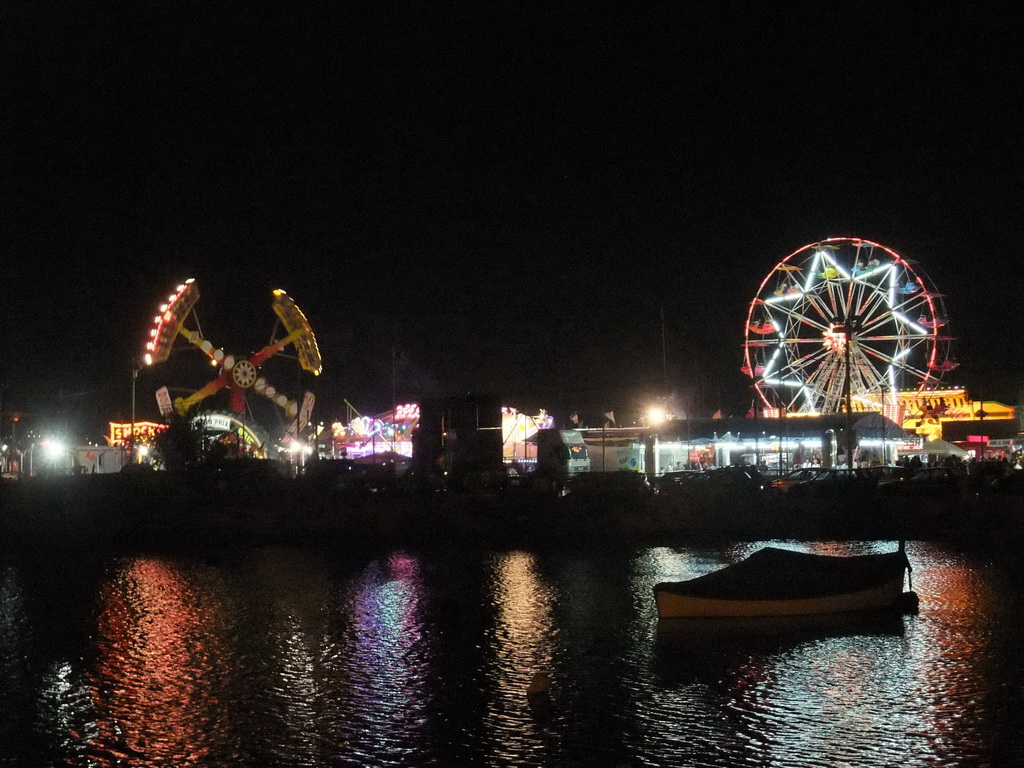 Boat in Marsamxett Harbour and Manoel Island with funfair attractions, by night