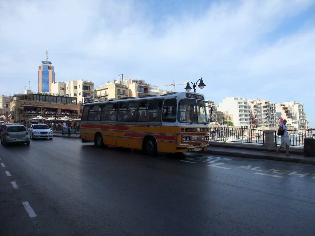 Yellow bus at Spinola Bay in St. Julian`s (San Giljan), with the Hilton Malta Hotel