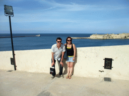 Tim and Miaomiao near the Siege Bell Monument at Valletta, with a view on the Grand Harbour with the pier at Fort Saint Elmo and the pier at Fort Ricasoli