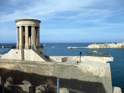 The Siege Bell Monument with the World War II Memorial, the Grand Harbour and Fort Ricasoli, viewed from the Lower Barracca Gardens at Valletta