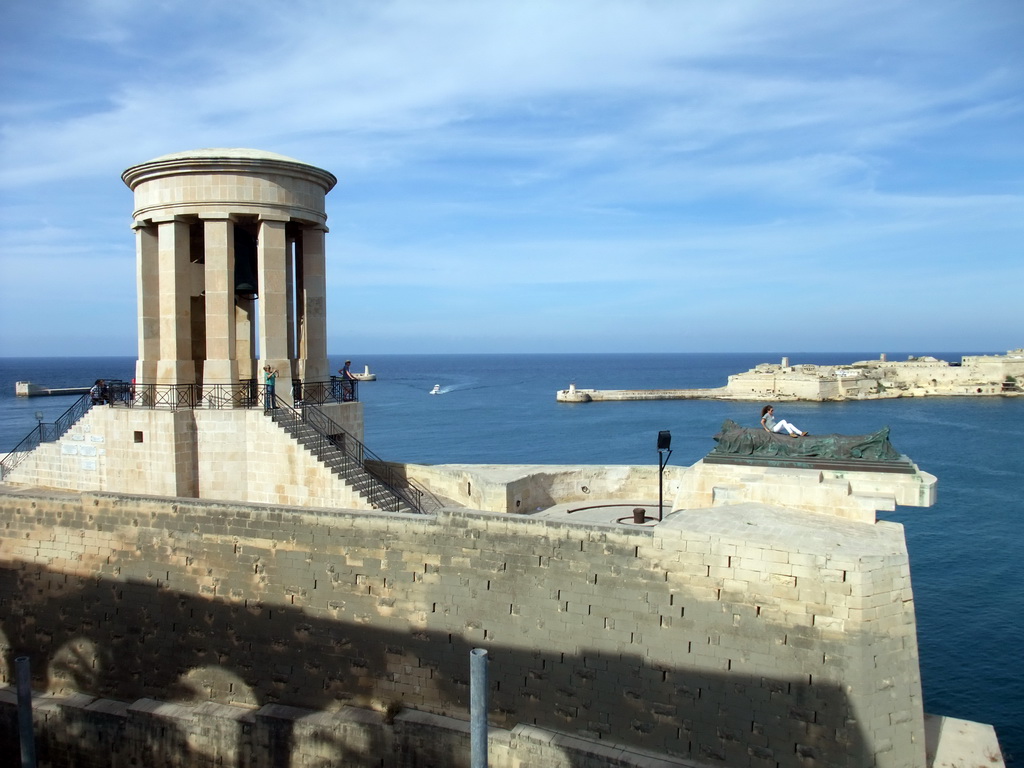 The Siege Bell Monument with the World War II Memorial, the Grand Harbour and Fort Ricasoli, viewed from the Lower Barracca Gardens at Valletta