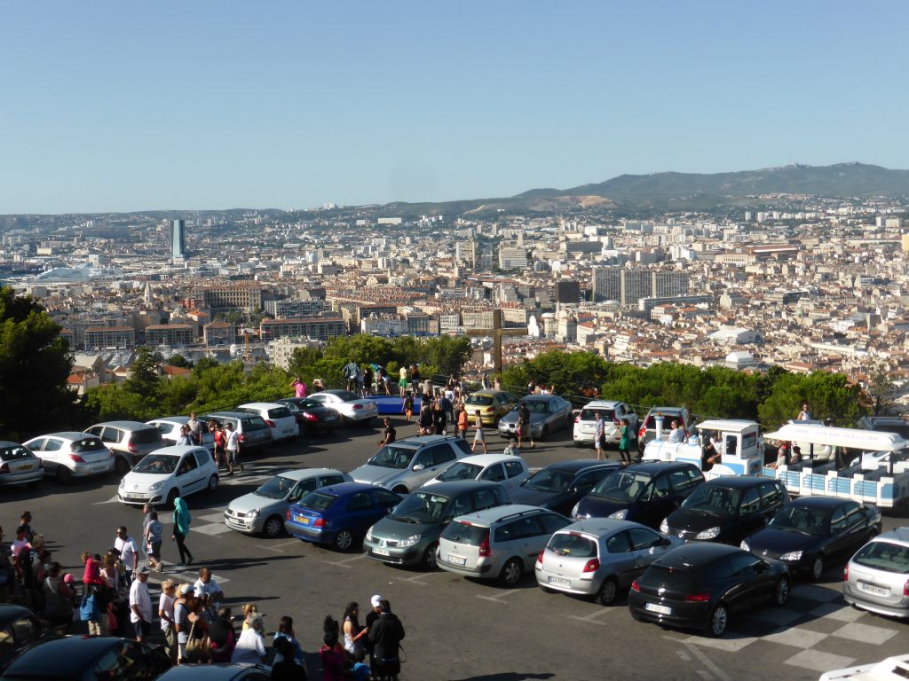 Tourist train and wooden cross at the square in front of the Notre-Dame de la Garde basilica, with a view on the city center