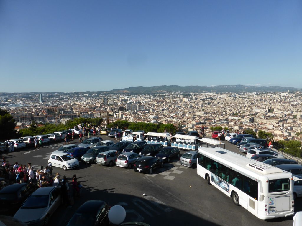 Tourist train and wooden cross at the square in front of the Notre-Dame de la Garde basilica, with a view on the city center