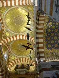 Small airplanes and boats hanging on the left side of the ceiling of the nace of the Notre-Dame de la Garde basilica