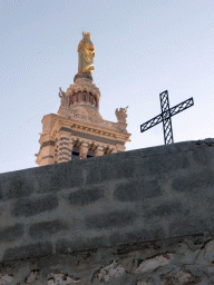 Wall, metal cross and the right side of the Statue of the Virgin with Child on top of the tower of the Notre-Dame de la Garde basilica