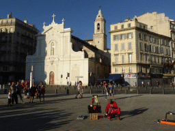 Street artist and the front of the Église des Augustins church at the Quai des Belges street