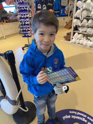 Max with the scavenger hunt, a medal and a plush Penguin at the souvenir shop of the Sea Life Porto