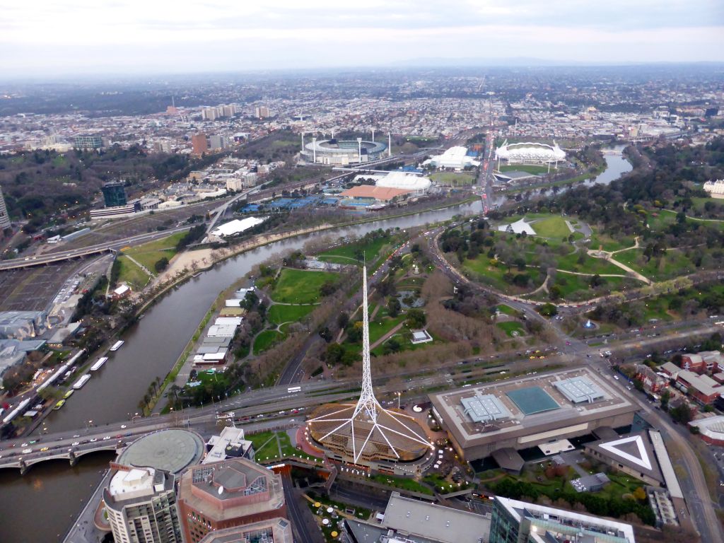 The Spire of the Arts Centre Melbourne, the National Gallery of Victoria, the Queen Victoria Gardens, the Kings Domain, the Melbourne Cricket Ground, the Rod Laver Arena, Melbourne Park, the Hisense Arena, the AAMI Park, the Fitzroy Gardens and the Yarra River, viewed from the Skydeck 88 of the Eureka Tower, at sunset