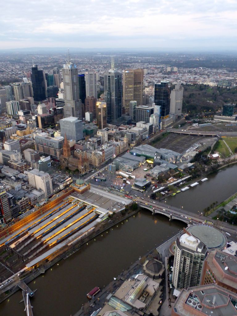 Skyscrapers at the city center, the Flinders Street Railway Station, St. Paul`s Cathedral, Federation Square with the Australian Centre for the Moving Image, the Princess Bridge over the Yarra River and the Fitzroy Gardens, viewed from the Skydeck 88 of the Eureka Tower, at sunset