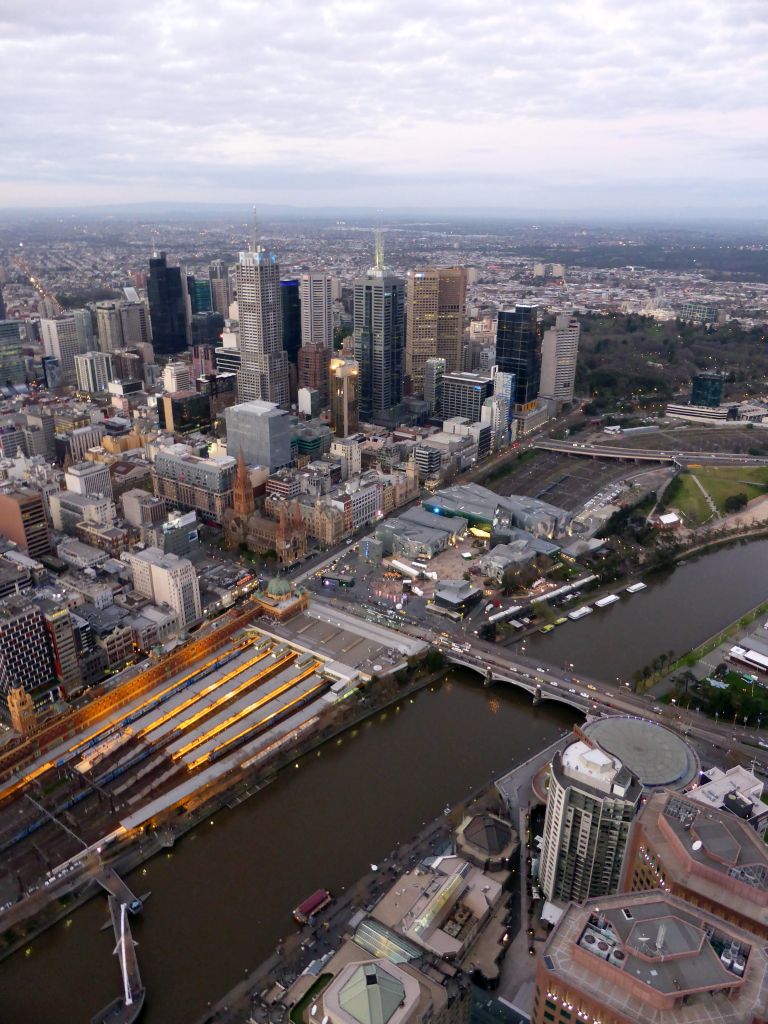 Skyscrapers at the city center, the Flinders Street Railway Station, St. Paul`s Cathedral, Federation Square with the Australian Centre for the Moving Image, the Southgate pedestrian bridge and the Princess Bridge over the Yarra River and the Fitzroy Gardens, viewed from the Skydeck 88 of the Eureka Tower, at sunset