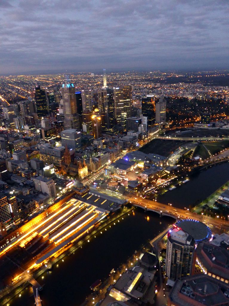 Skyscrapers at the city center, the Flinders Street Railway Station, St. Paul`s Cathedral, Federation Square with the Australian Centre for the Moving Image, the Princess Bridge over the Yarra River and the Fitzroy Gardens, viewed from the Skydeck 88 of the Eureka Tower, at sunset