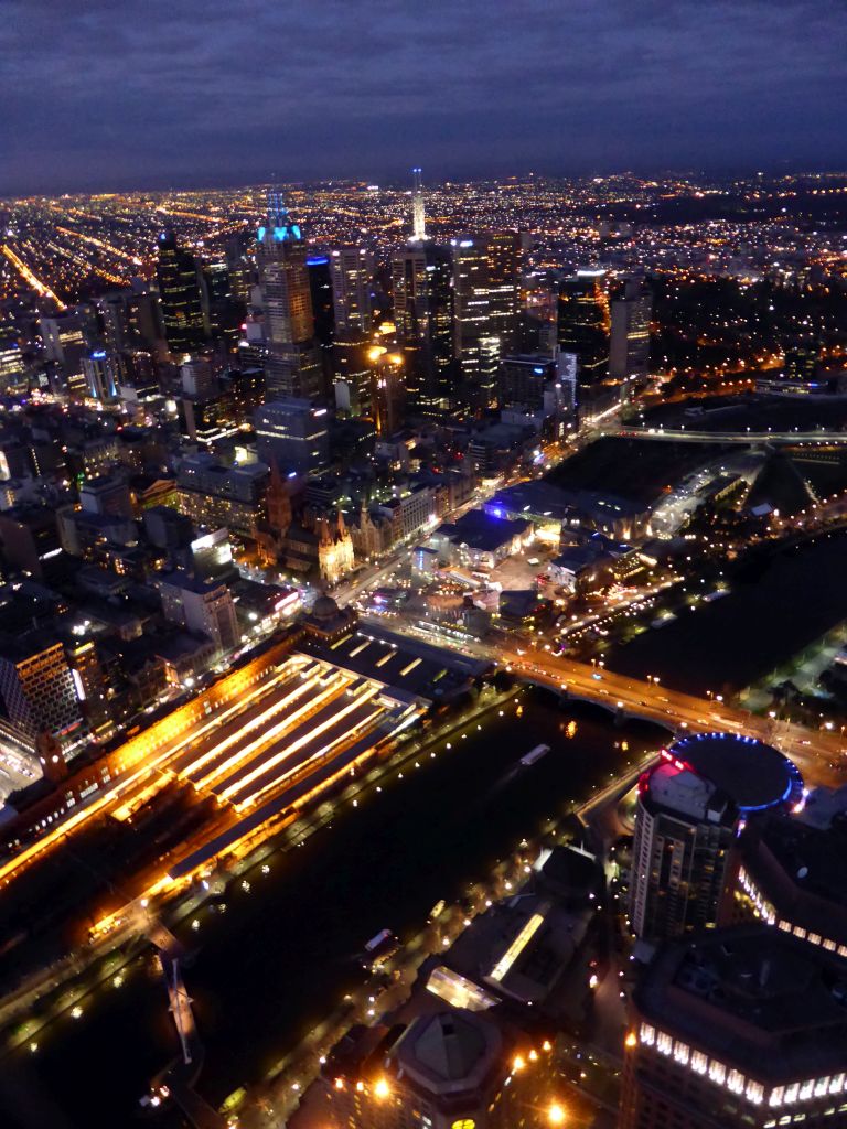 Skyscrapers at the city center, the Flinders Street Railway Station, St. Paul`s Cathedral, Federation Square with the Australian Centre for the Moving Image, the Southgate pedestrian bridge and the Princess Bridge over the Yarra River and the Fitzroy Gardens, viewed from the Skydeck 88 of the Eureka Tower, by night