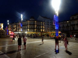 The Place de la Comédie square with the Three Graces Fountain and a tram, by night