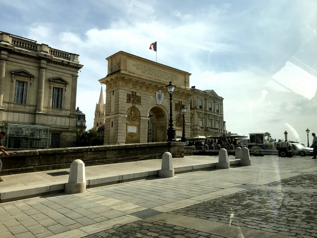 Tourist train and back side of the Porte du Peyrou arch at the Rue la Blottière street, viewed from the taxi to the airport