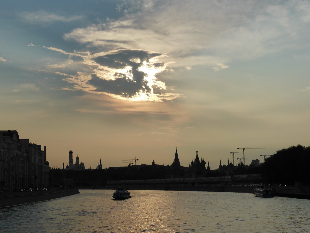 Sun behind the clouds above the Moskva river and the towers of the Moscow Kremlin and Saint Basil`s Cathedral, viewed from the tour boat