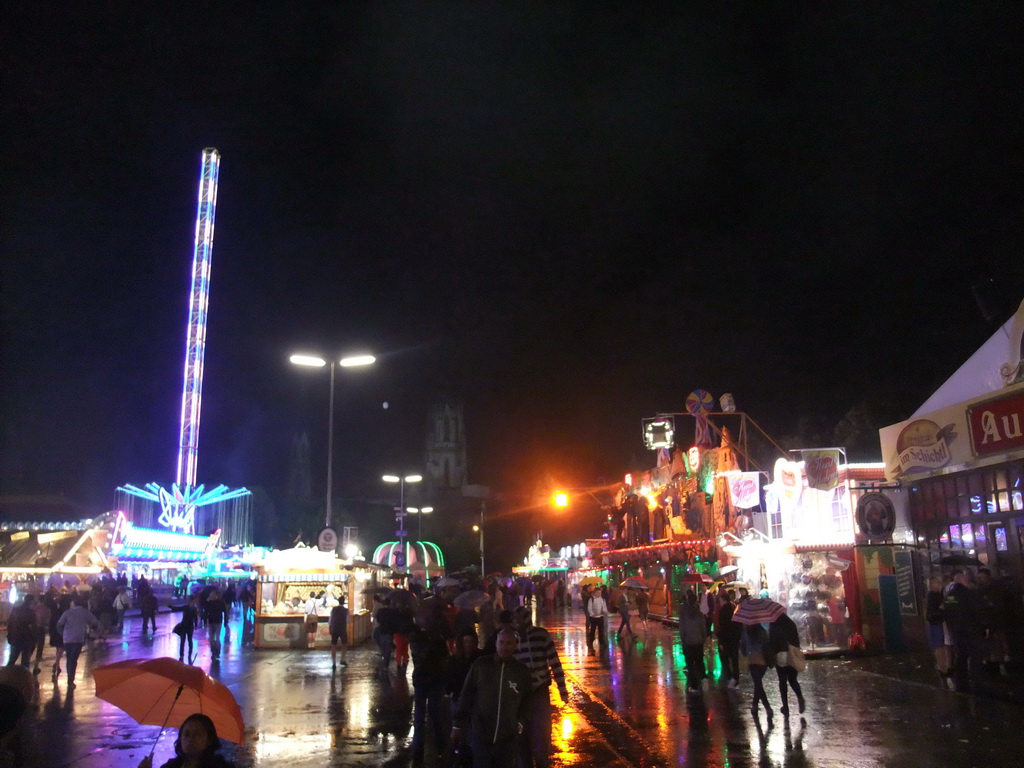Funfair at the Oktoberfest terrain at the Theresienwiese square and St. Paul`s Church, by night