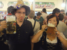 Miaomiao and a friend with beers, and people celebrating the Oktoberfest festival in the Paulaner tent at the Oktoberfest terrain at the Theresienwiese square