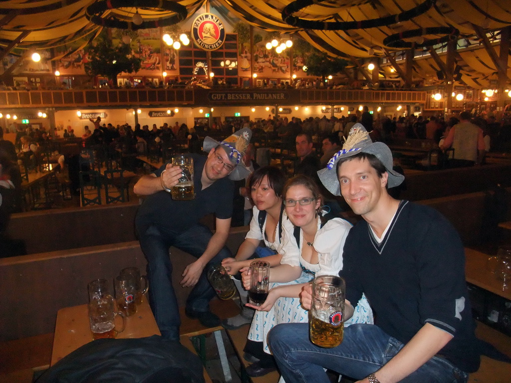 Tim, Miaomiao and friends with beers, and people celebrating the Oktoberfest festival in the Paulaner tent at the Oktoberfest terrain at the Theresienwiese square