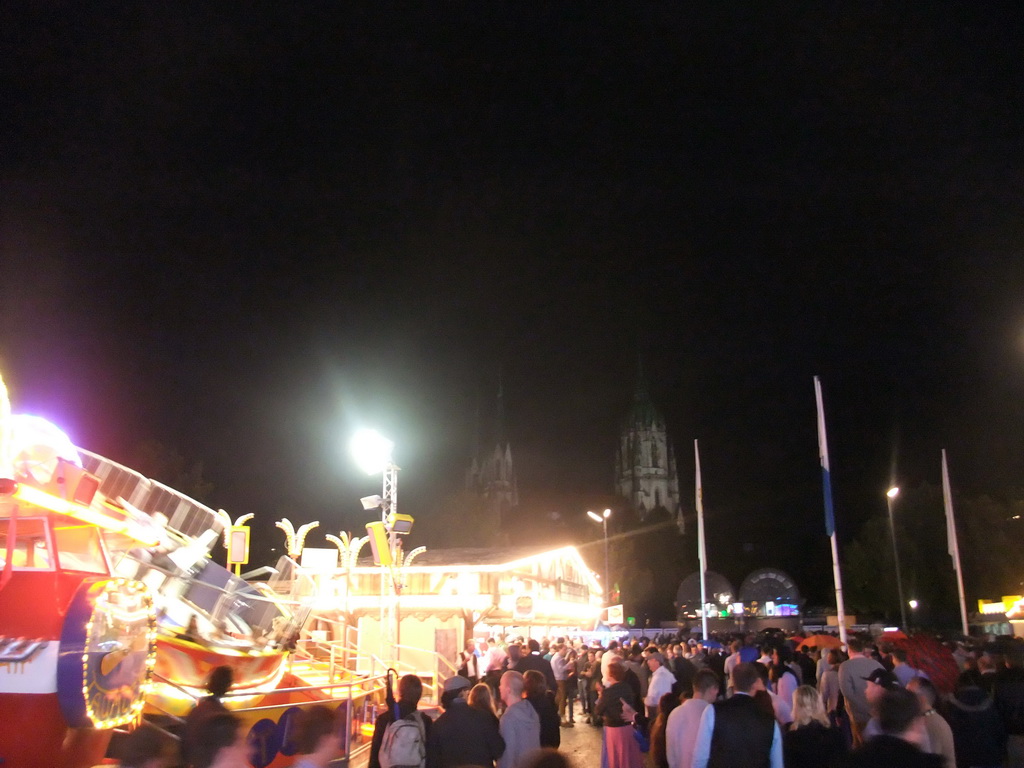 Funfair at the Oktoberfest terrain at the Theresienwiese square and St. Paul`s Church, by night