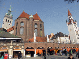Shops at the Viktualienmarkt square, with a view on the tower and back side of St. Peter`s Church, and the tower of the Altes Rathaus building