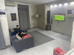 Max watching football in the living room of the House of Mola apartment