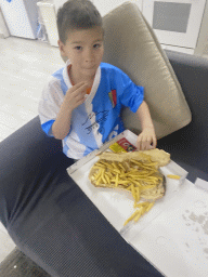 Max eating pizza with fries in the living room of the House of Mola apartment