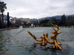 Central Fountain with a statue of a dragon at the Parc Phoenix zoo, and the Porte de l`Arénas building