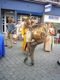 Person in medieval clothes carrying stuff on his back at the Houtstraat street, during the Gebroeders van Limburg Festival