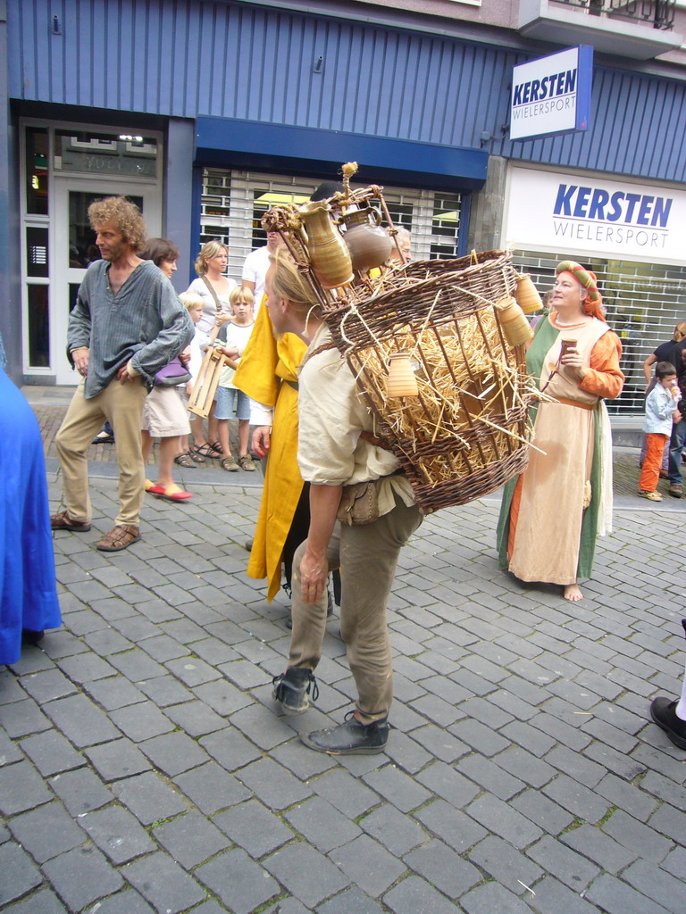 Person in medieval clothes carrying stuff on his back at the Houtstraat street, during the Gebroeders van Limburg Festival