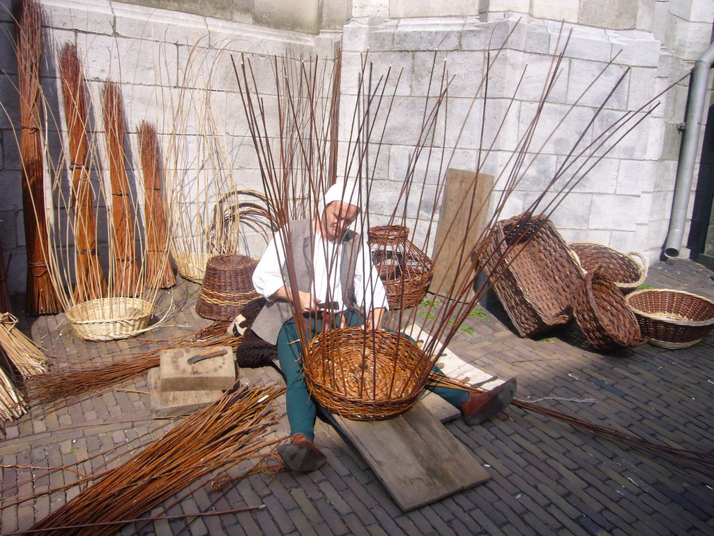 Person in medieval clothes making rush baskets in front of the Sint Stevenskerk church at the Sint Stevenskerkhof square, during the Gebroeders van Limburg Festival
