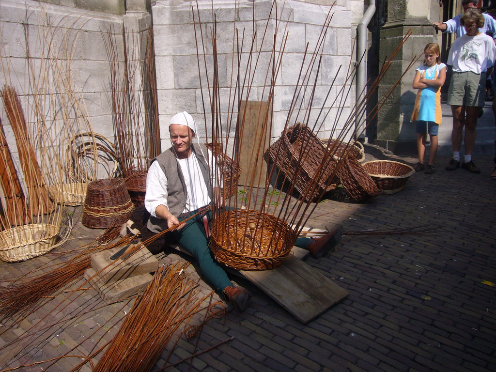 Person in medieval clothes making rush baskets in front of the Sint Stevenskerk church at the Sint Stevenskerkhof square, during the Gebroeders van Limburg Festival