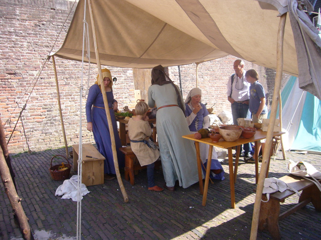 People in medieval clothes eating in front of the Sint Stevenskerk church at the Sint Stevenskerkhof square, during the Gebroeders van Limburg Festival