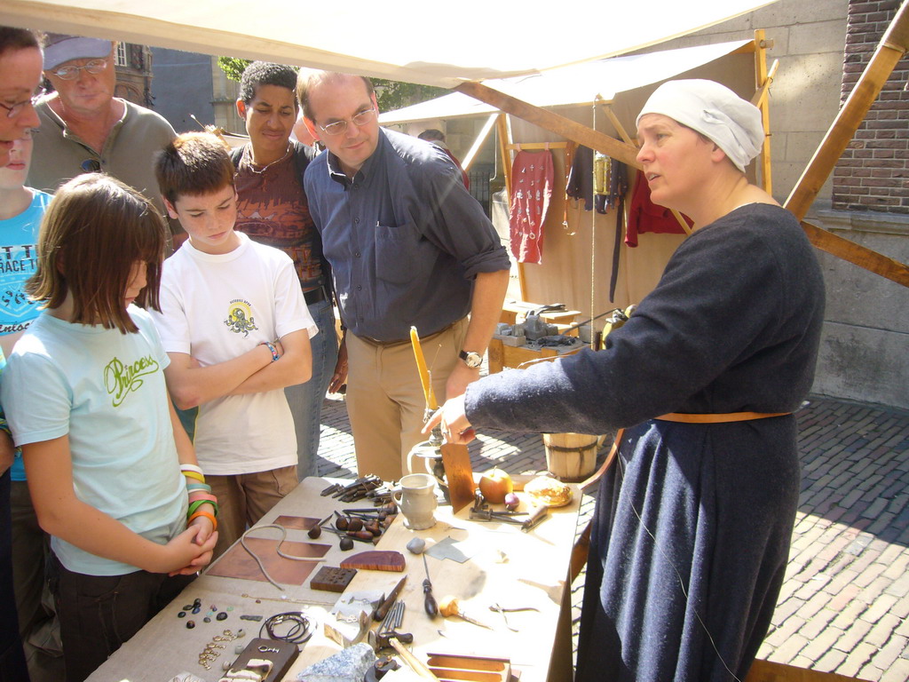 Person in medieval clothes making jewellery in front of the Sint Stevenskerk church at the Sint Stevenskerkhof square, during the Gebroeders van Limburg Festival