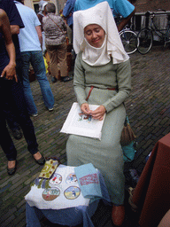 Person in medieval clothes making clothes at the Sint Stevenskerkhof square, during the Gebroeders van Limburg Festival