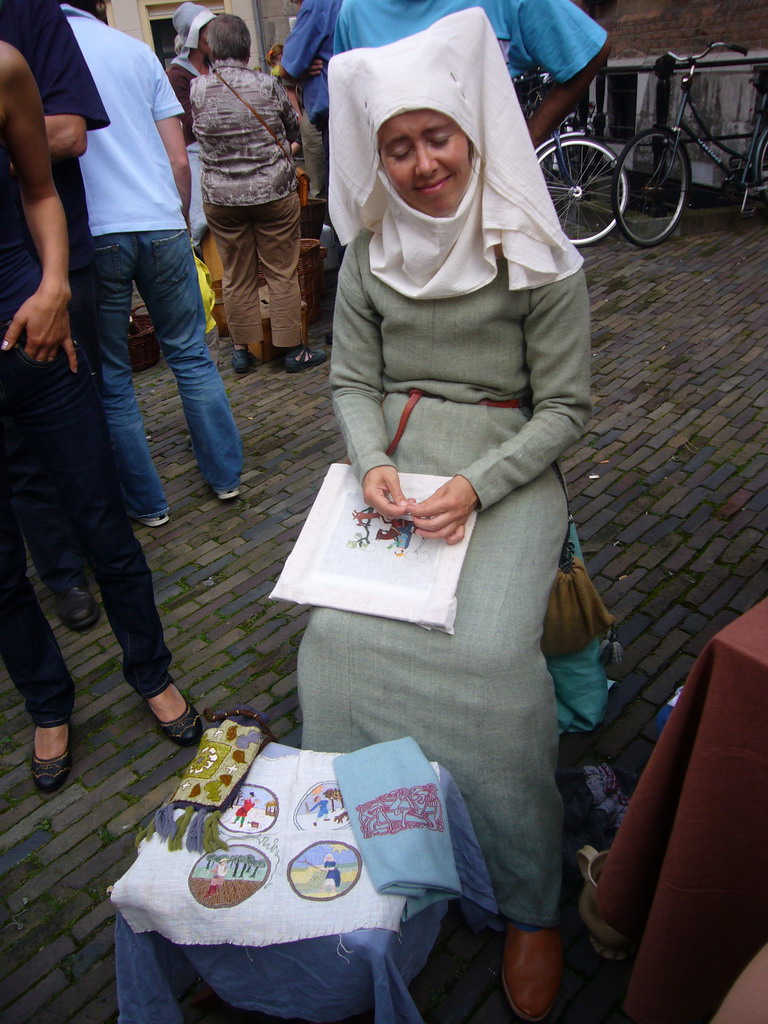 Person in medieval clothes making clothes at the Sint Stevenskerkhof square, during the Gebroeders van Limburg Festival