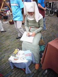 Person in medieval clothes making clothes at the Sint Stevenskerkhof square, during the Gebroeders van Limburg Festival