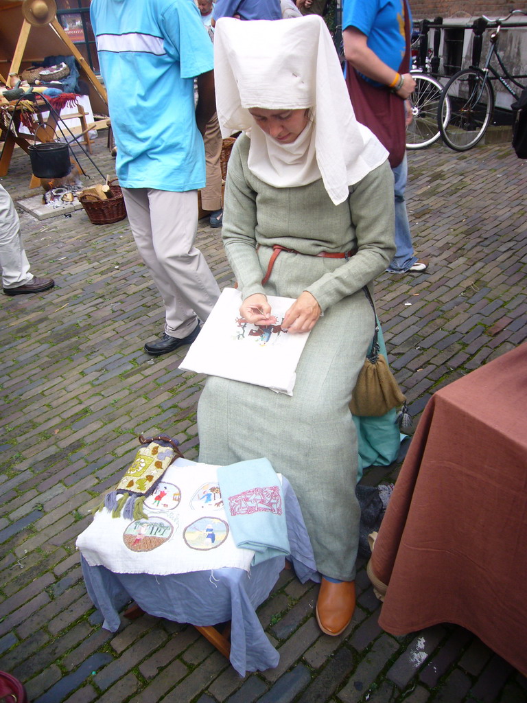 Person in medieval clothes making clothes at the Sint Stevenskerkhof square, during the Gebroeders van Limburg Festival