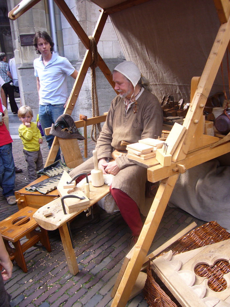 Person in medieval clothes processing wood at the Sint Stevenskerkhof square, during the Gebroeders van Limburg Festival