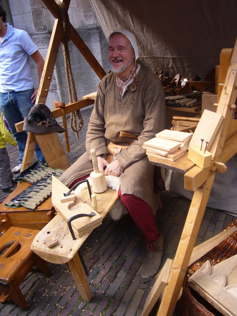 Person in medieval clothes processing wood at the Sint Stevenskerkhof square, during the Gebroeders van Limburg Festival