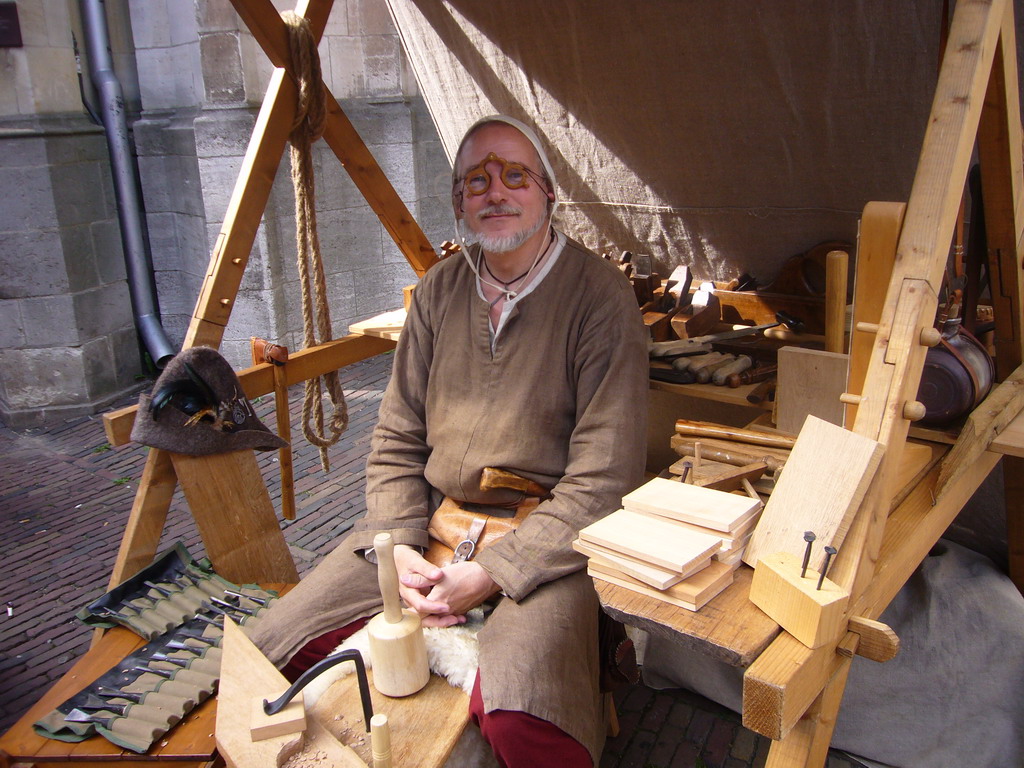Person in medieval clothes processing wood at the Sint Stevenskerkhof square, during the Gebroeders van Limburg Festival